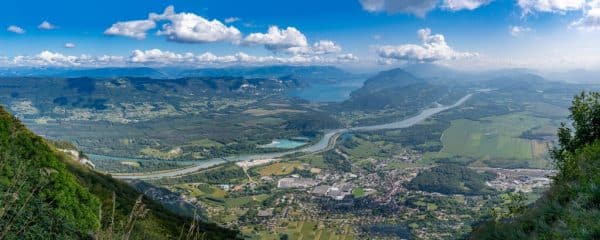 Camping Le Colporteur Ciela Village Grand Colombier Pass. View of the forest, the road, the Rhone river, the Lake Bourget, the mountains and Culoz city behind